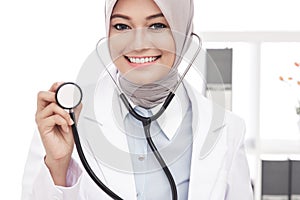 Asian female doctor smiling while using stethoscope