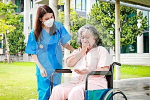 Asian female doctor in surgical gown caring for an elderly female patient