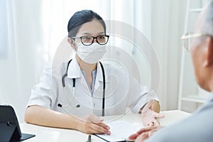 Asian Female Doctor talking to senior man patient.