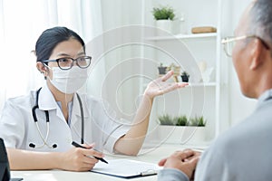 Asian Female Doctor talking to senior man patient.