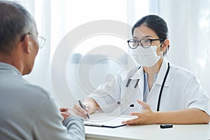 Asian female doctor talking to senior man patient.