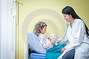 Asian female doctor uses stethoscope to check the heartbeat. Little girl