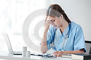 Asian female doctor working on laptop, filling out paperwork, patient medical history, reviewing documents at her