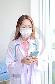 Asian female doctor working in office Wearing a mask, holding a smartphone