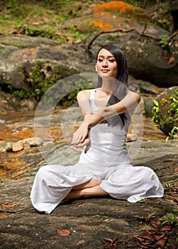 Asian female doing yoga in a park