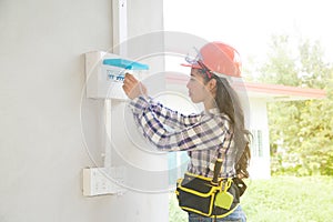 Asian female Electrician or Engineer check or Inspect Electrical system circuit Breaker.