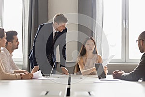 Asian female employee presenting report to boss at group meeting