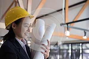 Asian female engineer holding construction blueprint. architect