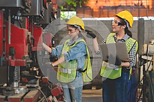 Asian female engineer with laptop training female worker uses a machine in factory Industrial