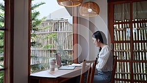 An Asian female entrepreneur working at cafe using a calculator to budget