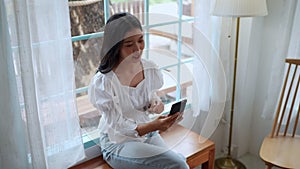 Asian female entrepreneur working at cafe video calls on her smartphone