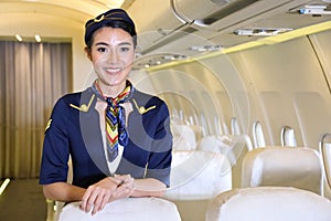 Asian female flight attendant posing with smile inside the aircraft to welcome all the passenger photo