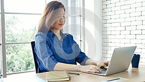 Asian Female freelance using laptop at home office desk. Woman reading financial graph chart Planning analyzing marketing data.