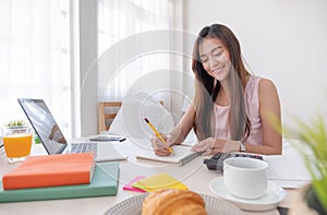 Asian female freelancer working on laptop computer on table at bedroom at home.working online lifestyle.working at home