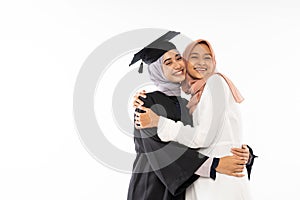 Asian female graduate student wearing toga hugging her sister