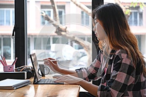 Asian female graphic designer using stylus pen writing on digital tablet.