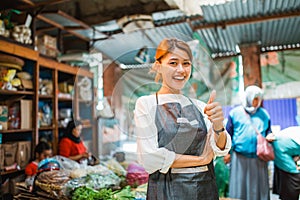 asian female greengrocery seller standing with thumb up gesture