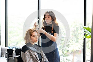 Asian female hairdresser make hairstyles for lady customers in modern beauty salons in Bangkok city. photo