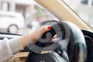 Asian female hands on the steering wheel of a car while driving with windshield and road. Black woman hands holding a steering