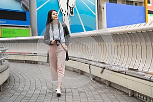 Asian female holding a camera on the bridge.