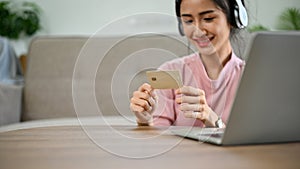 Asian female holding a credit card, spending her weekend on online shopping website