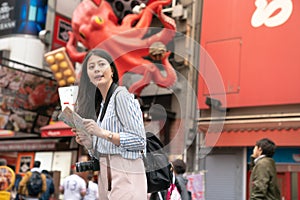 Asian female holding a map and looking for a place.