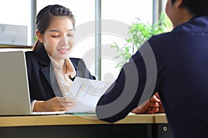 Asian female from human resource team is looking on the resume of new male applicant who wearing formal to the job inte