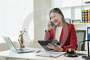 Asian female lawyer working in office or court with hammer and justice pad on table, online l