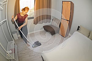 Asian maid Cleaning Service with Mop cleaning floor on a bedroom.