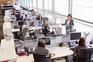 Asian female manager addressing workers in open plan office photo