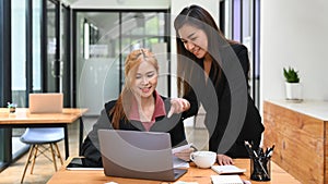 Asian female manager helping, giving advices to young intern at cooperate office