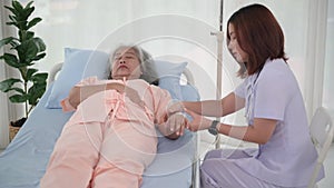 Asian female nurse gives saline solution to senior woman patient