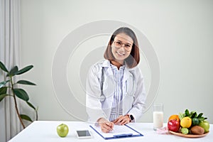 Asian Female nutritionist with fruits working at her desk. Health care and diet concept