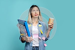 Asian female office worker is bored with a lot of paperwork at hand. She looks up, standing  on a pastel blue background