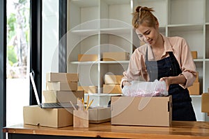 Asian female online store small business owner seller entrepreneur packing package post shipping box preparing delivery