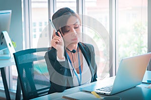 Female operator is talking on the phone to service client in the telemarkerting office