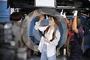 Asian female owner and mechanical worker team, check car undercarriage.