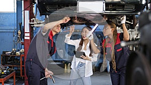 Asian female owner and mechanical worker team, check car undercarriage.