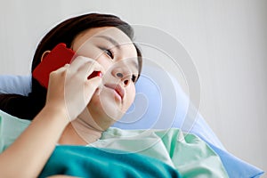 Asian female patient getting sick and lying on bed in hospital with unhappy and unwell condition while talking or communicating on