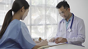 Asian female patient sitting at a table listening to a medical professional with a stethoscope explaining