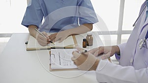 Asian female patient sitting at a table listening to a medical professional with a stethoscope explaining