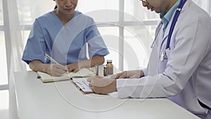 Asian female patient sitting at a table listening to a medical professional with a stethoscope explaining