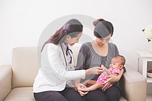Asian female pediatrician examining a baby girl in the mother la