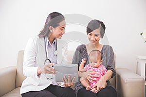 Asian female pediatrician showing something on tablet pc while a
