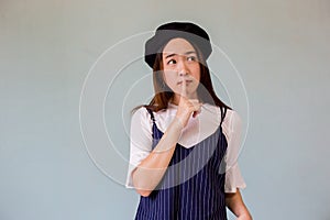 Asian female person with finger in mouth. Closeup portrait of young woman is showing a shh sign of silence, respecting woman`s se