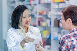 Asian female pharmacist or doctor explaining prescription medicine to patient female in a pharmacy