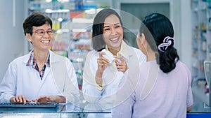 Asian female pharmacist or doctor explaining prescription medicine to patient female in a pharmacy