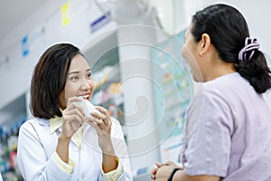 Asian female pharmacist explain details of the drug to female patients in pharmacy Thailand