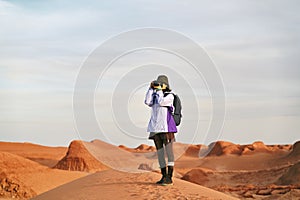 Asian female photographer taking picture of yardang landforms