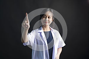 Asian female physician, Med student or resident doctors standing and pointing finger on black background.